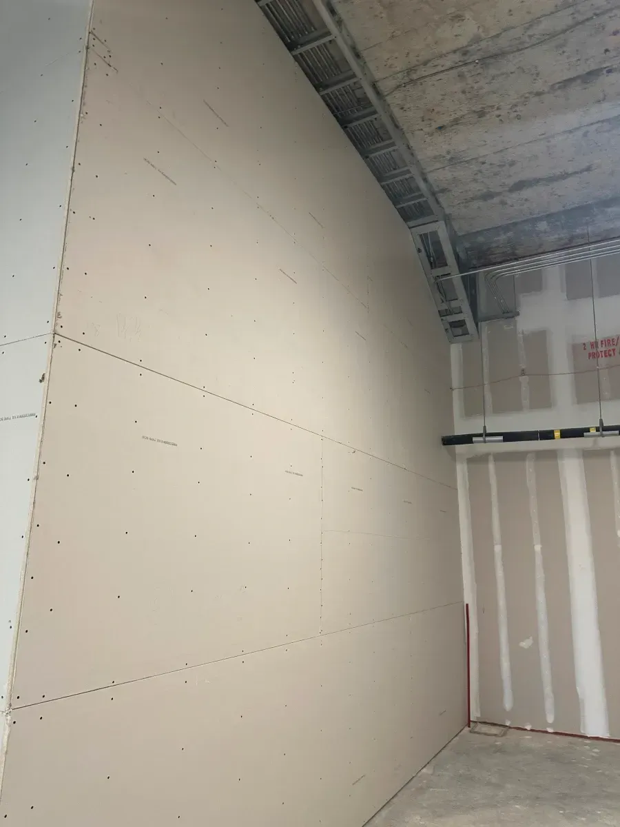 Drywall being installed on a curved interior wall, construction site.