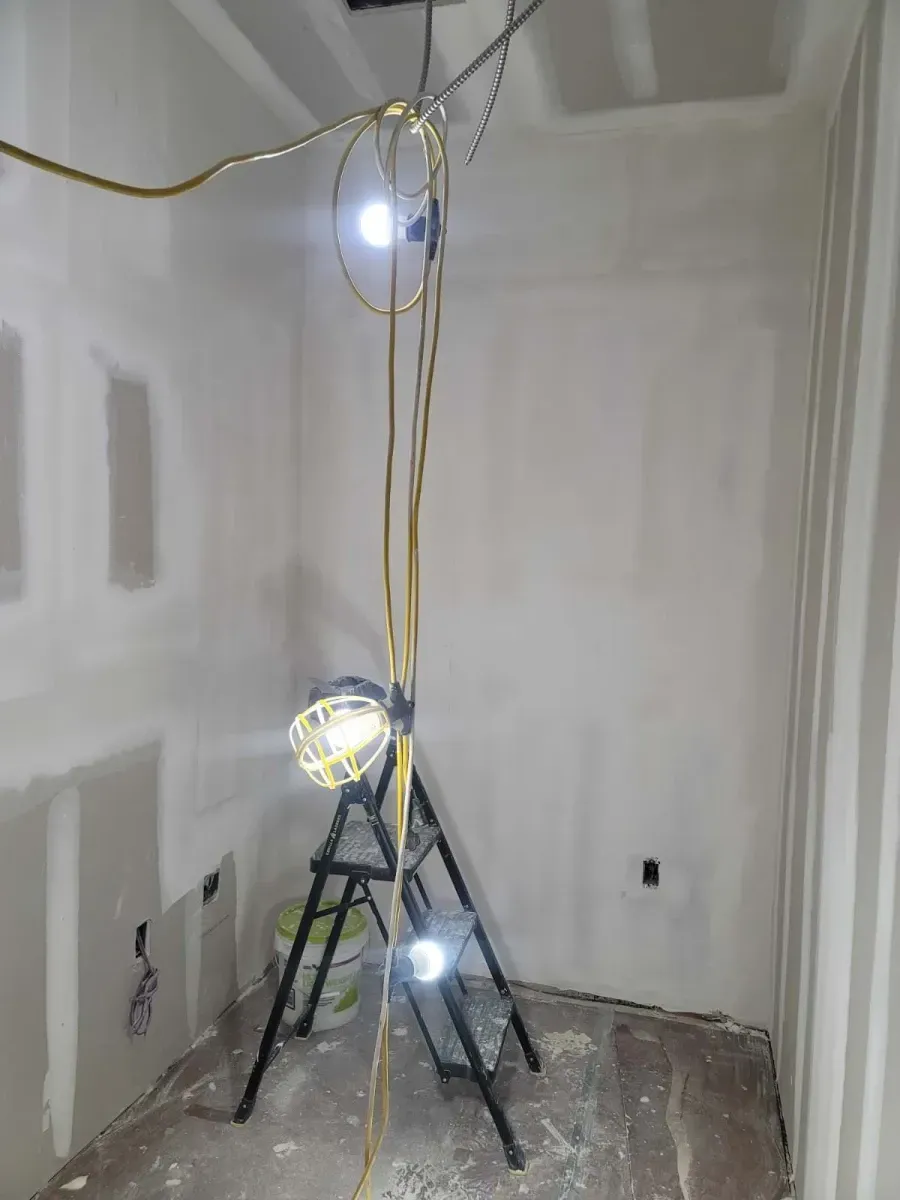 Interior under construction with a work light tripod illuminating drywall.