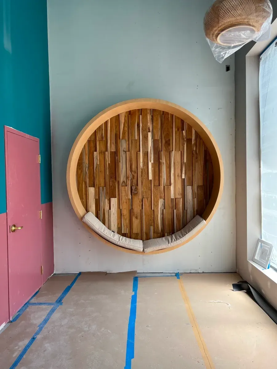 Circular wooden bench built into a wall, with two-tone green and pink walls.