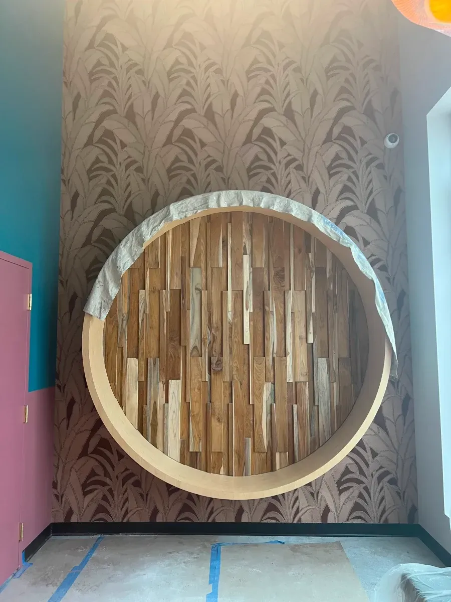Wooden circular wall fixture against patterned wallpaper and painted wall.