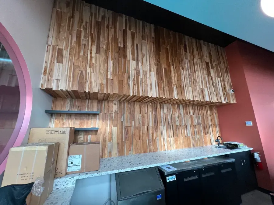 Wooden accent wall above a countertop in a commercial space, with shelves and boxes.