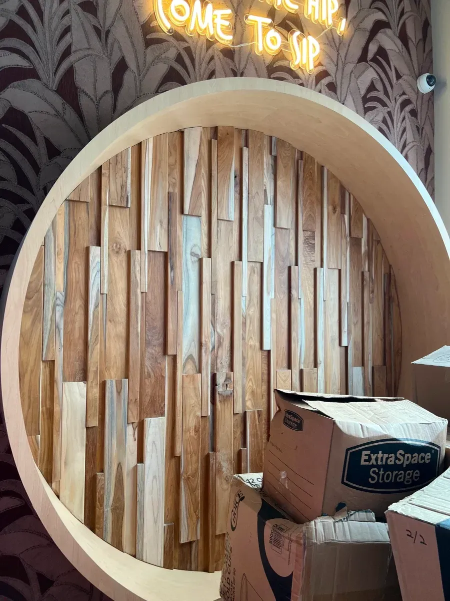 Circular wooden wall decor with vertical wood planks; boxes in front.