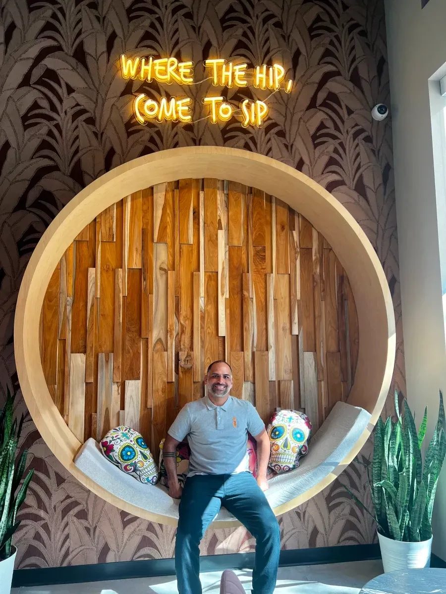 Man sitting in a circular booth with a wooden backdrop. 