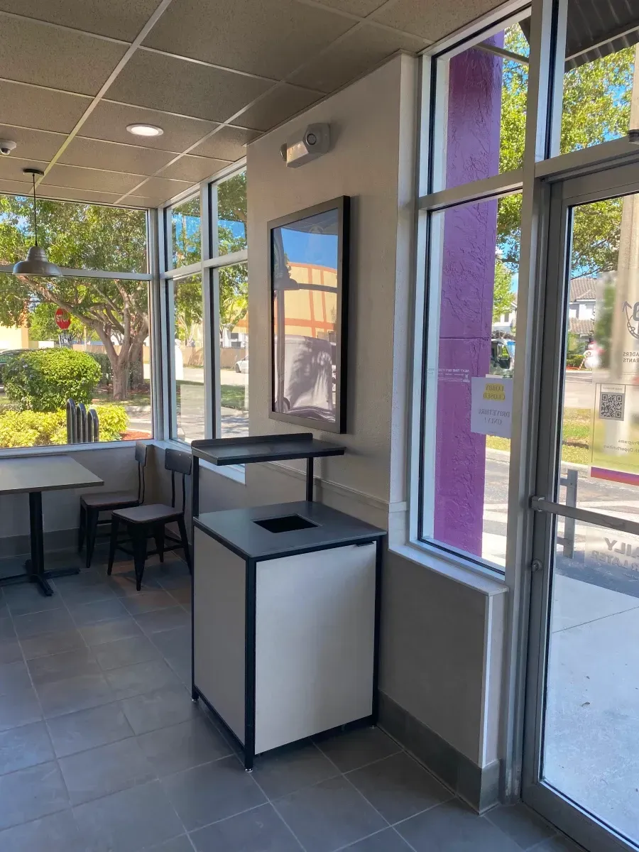 Restaurant interior with trash can, windows, and tables.
