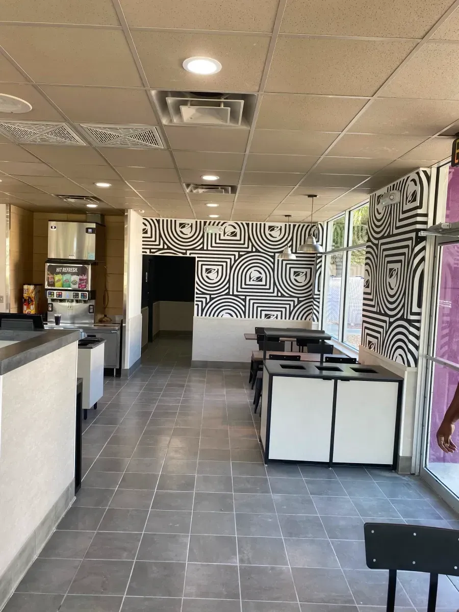 Interior of a restaurant with black and white abstract wall art, tables, and a tiled floor.
