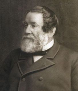 A sepia-toned portrait of a person with a full beard, wearing a dark buttoned coat and a high-collared shirt.