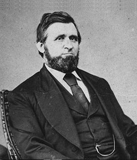 A historical portrait of a bearded man in a formal suit and necktie, sitting in a chair.