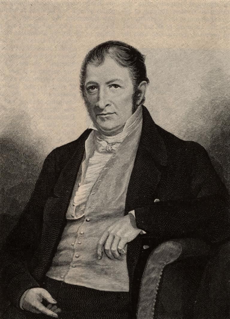 Portrait of Eli Whitney, shown from the chest up, wearing a dark coat and light vest against a neutral background.