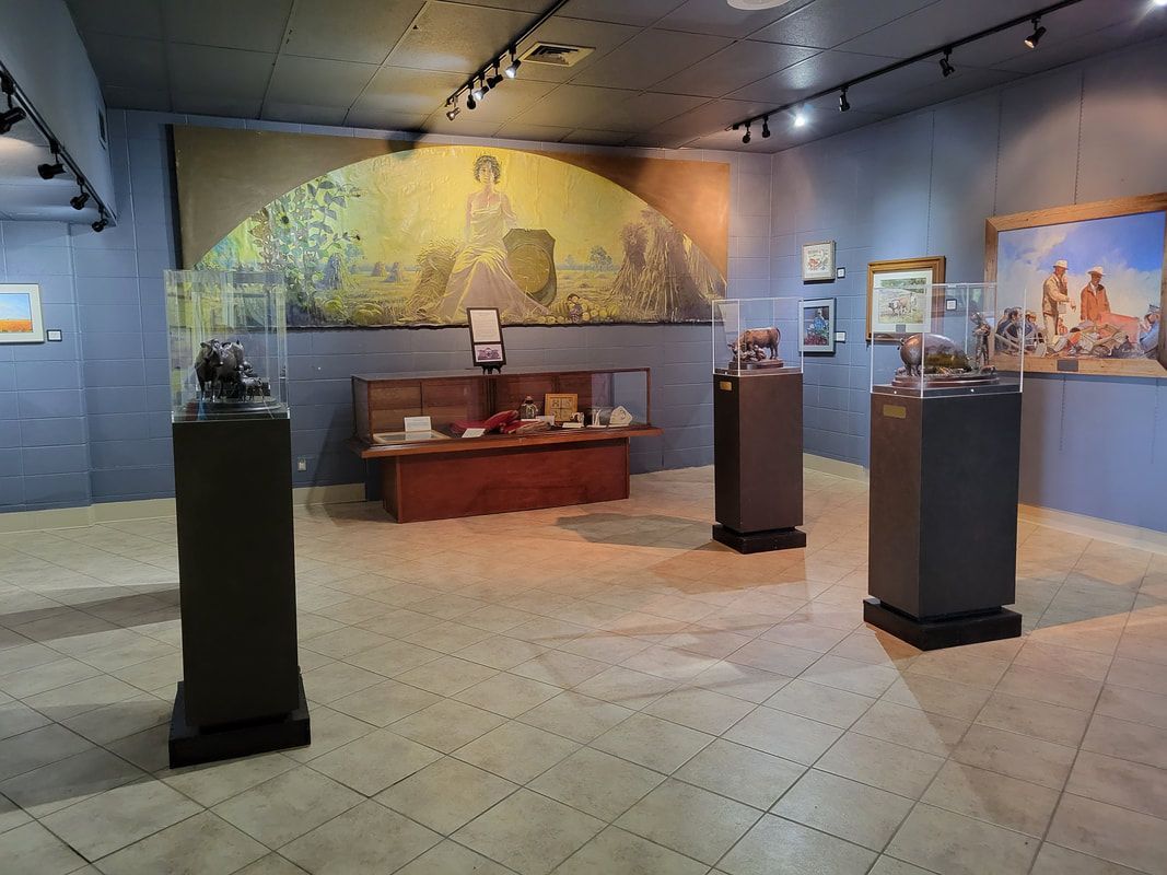 A museum gallery featuring a central mural, a display cabinet, and three pedestal-mounted sculptures on a tiled floor.