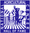 Blue and white logo of the National Agricultural Center and Hall of Fame featuring a farmer, a tractor, crops, and a cow.