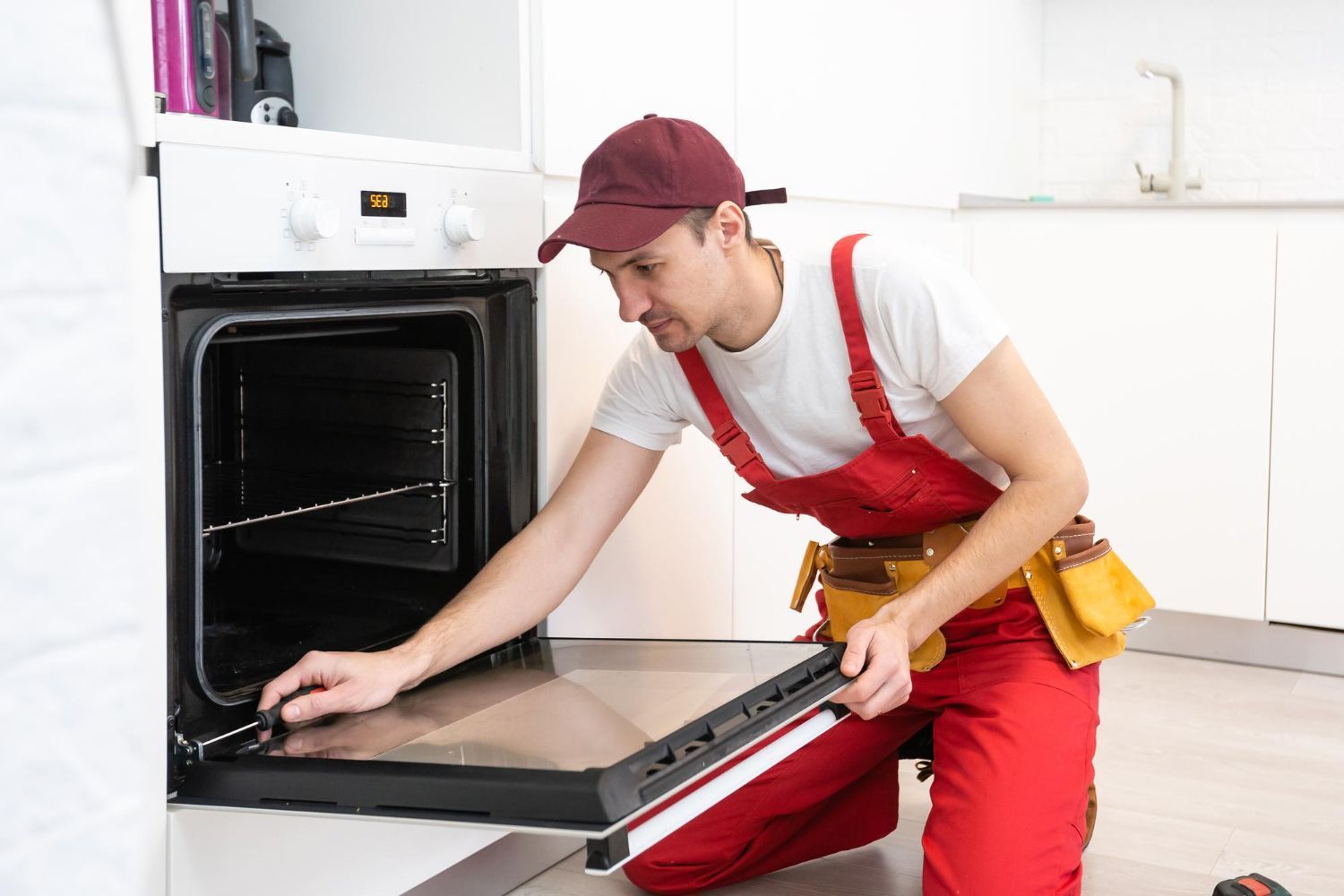 A Man Is Fixing An Oven In A Kitchen