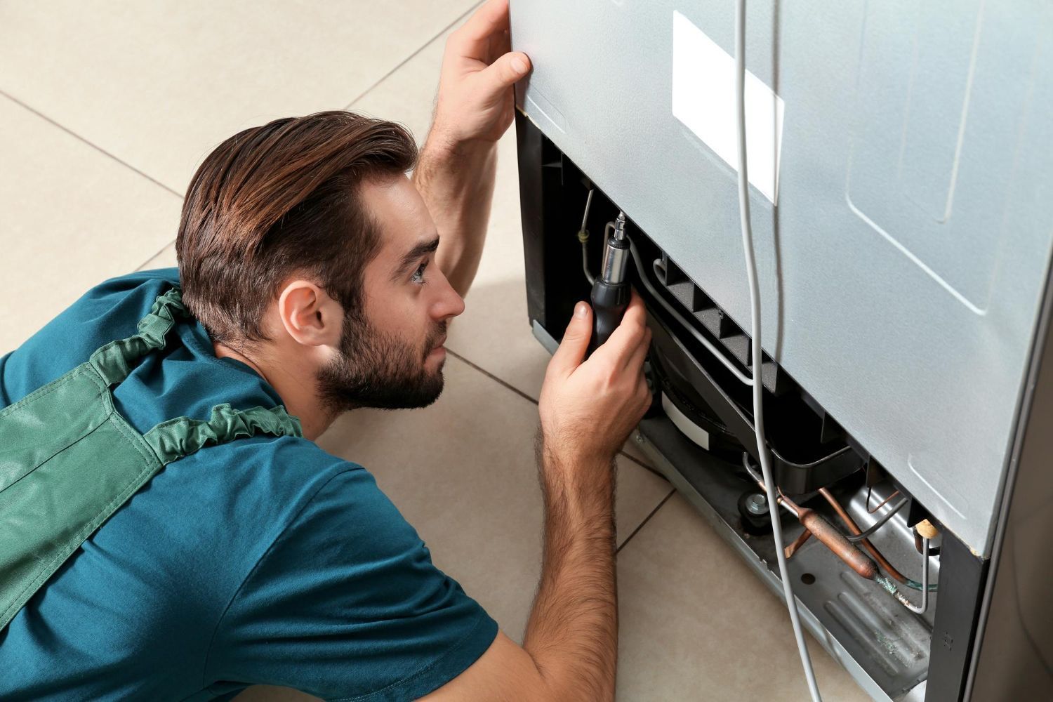 a man is fixing a refrigerator on the floor