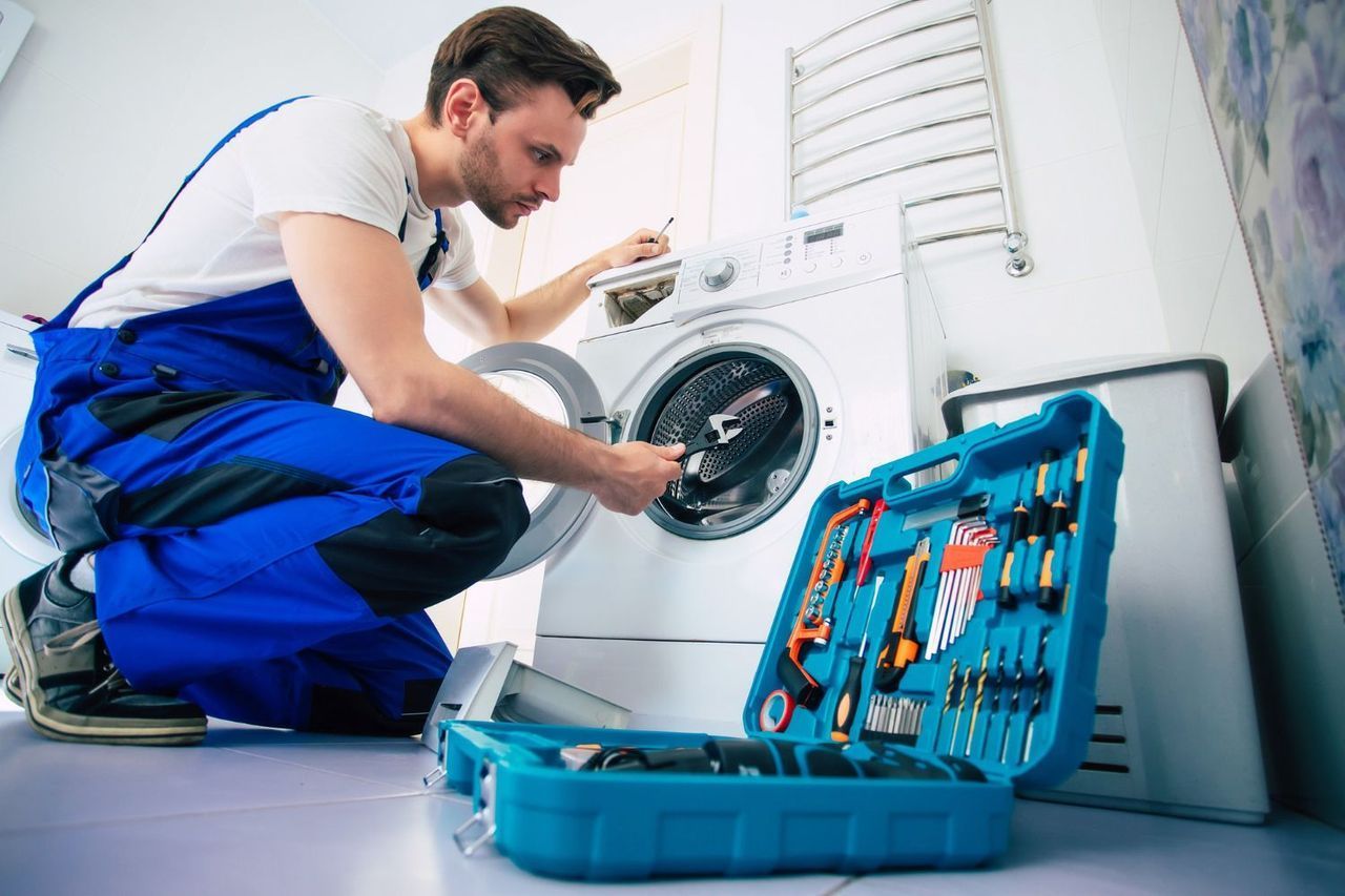a man is fixing a washing machine in a bathroom