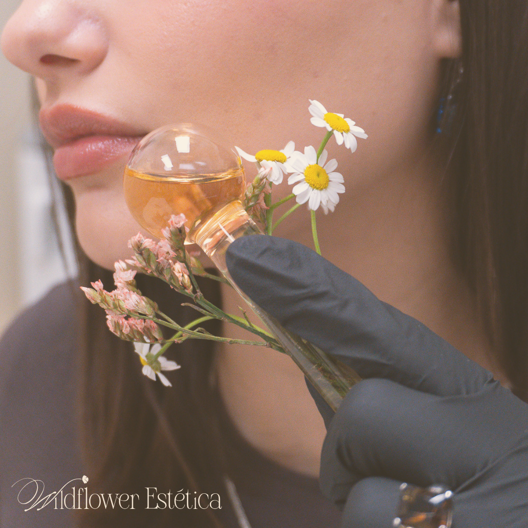 A woman wearing black gloves is holding a bottle of perfume with flowers in it