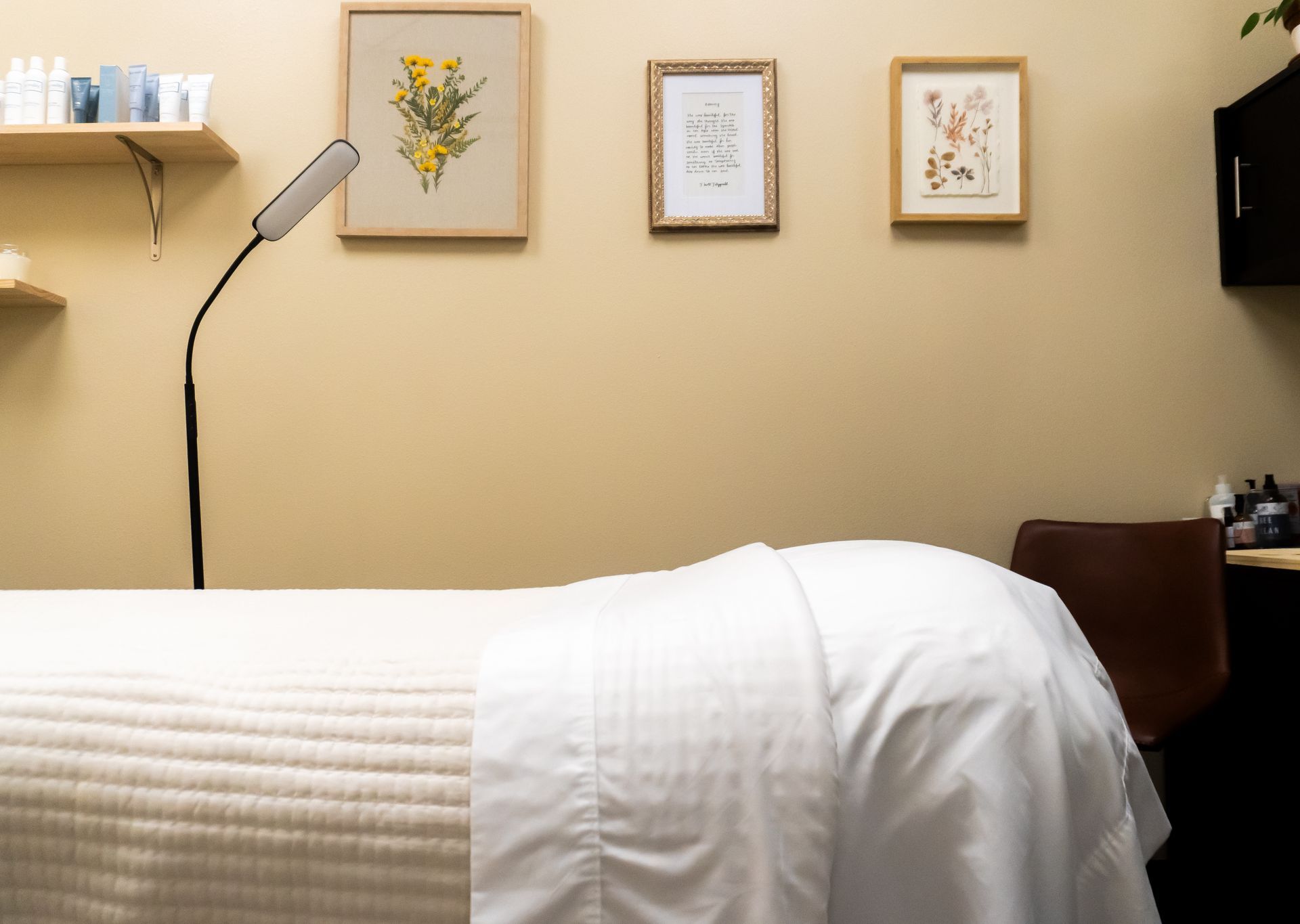 Treatment room with massage table, framed art, and a flexible lamp.