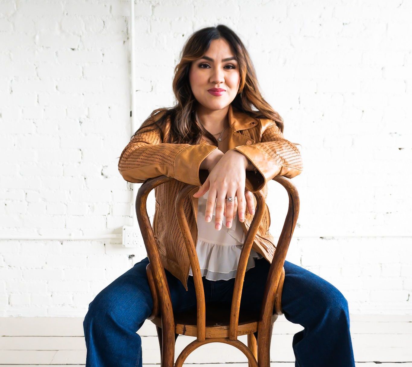 A woman is sitting in a chair with her hands on her hips.