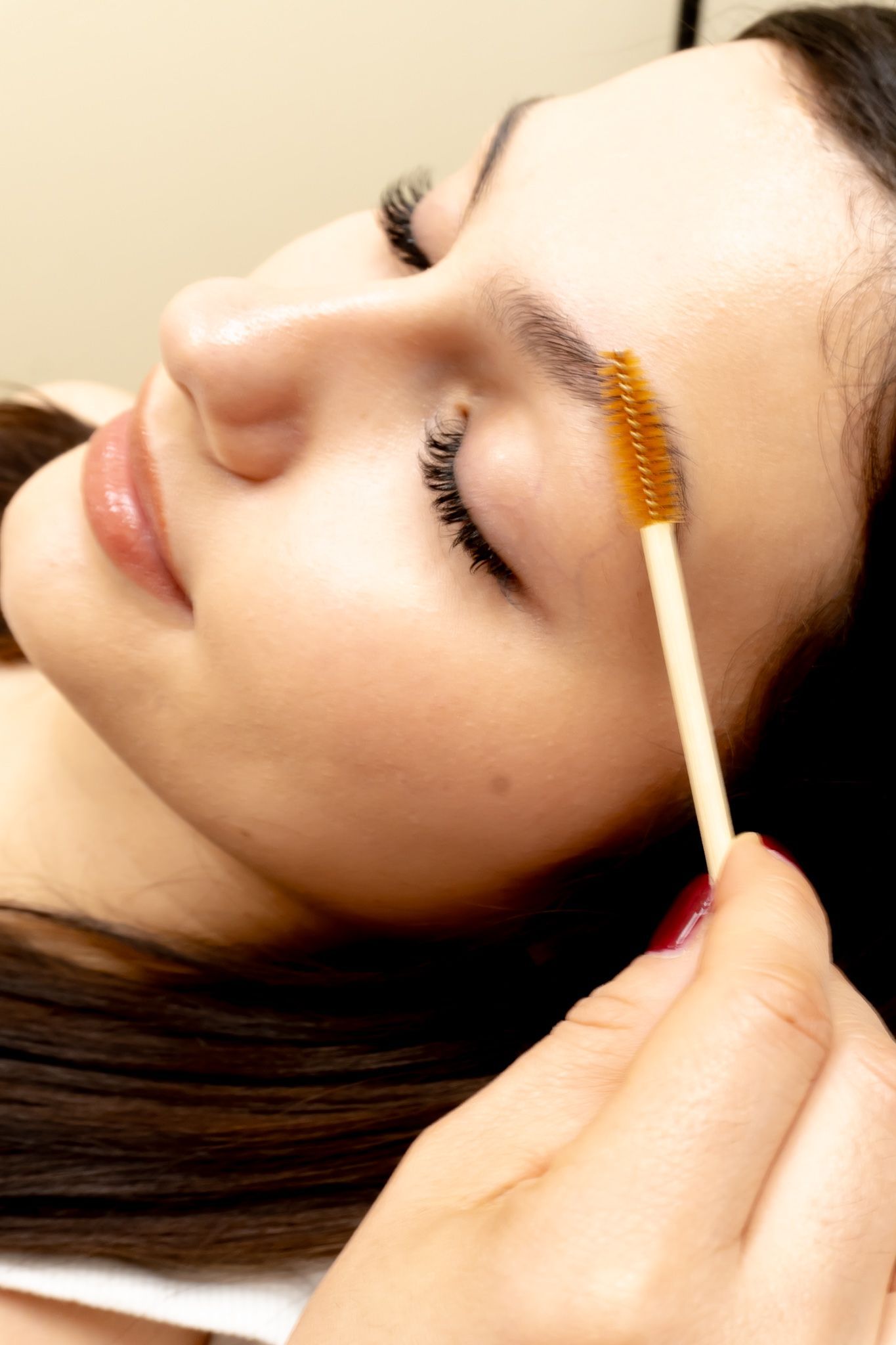 A woman is getting her eyebrows done with a brush