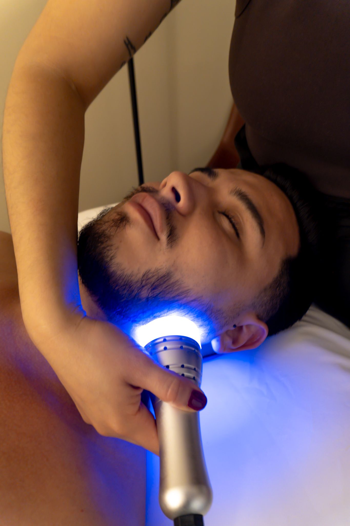 A man is getting a blue light treatment on his face.