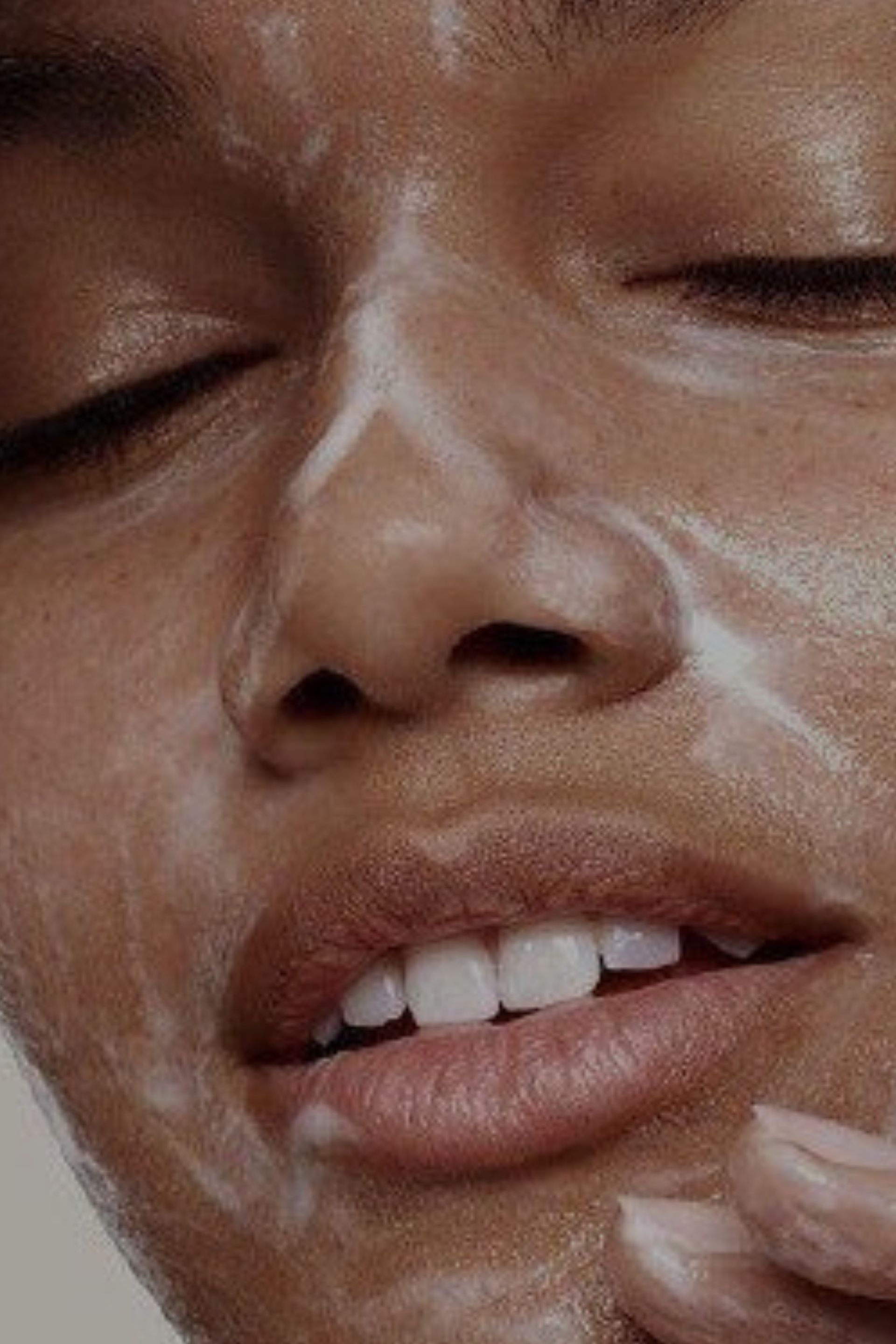 Person's face covered in white cleanser, eyes closed, lips slightly open.