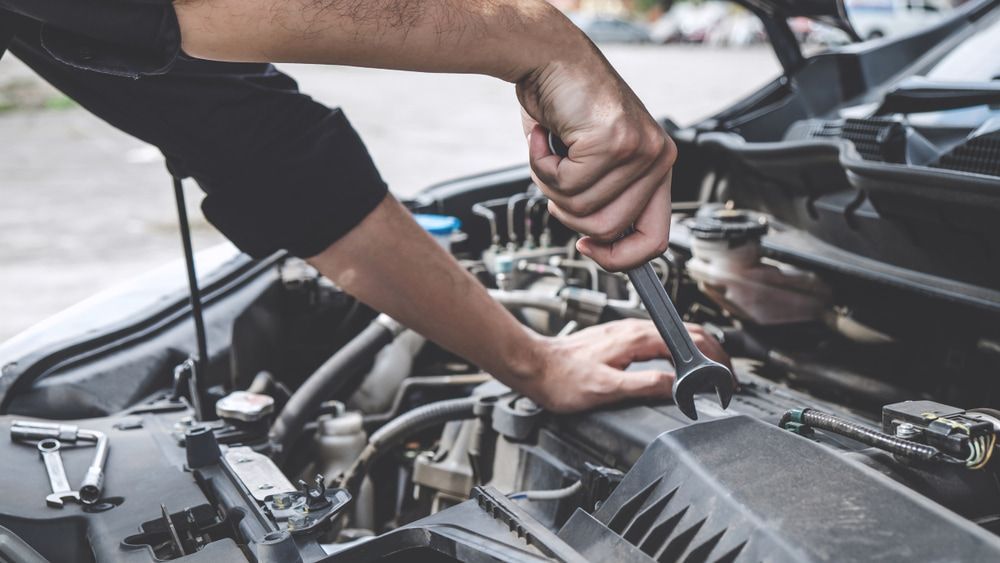 A Man Is Working On The Engine Of A Car With A Wrench — AMC Diesel Fuel Injection Services In Paget, QLD