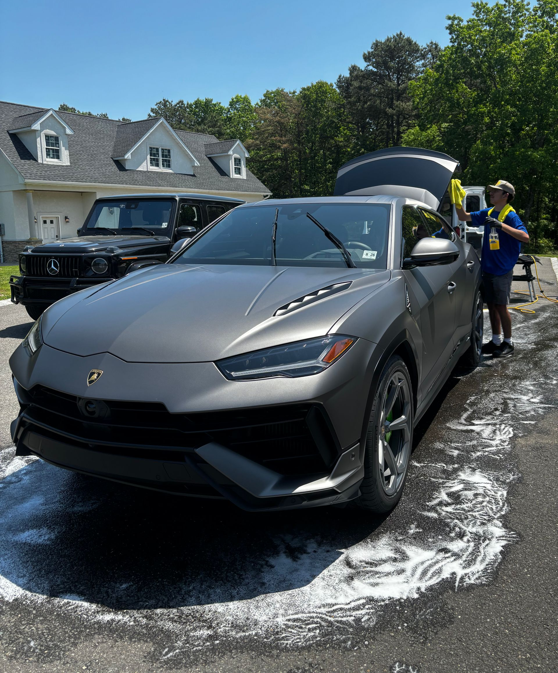 Technicians performing mobile car detailing on luxury sedan at customer’s home.