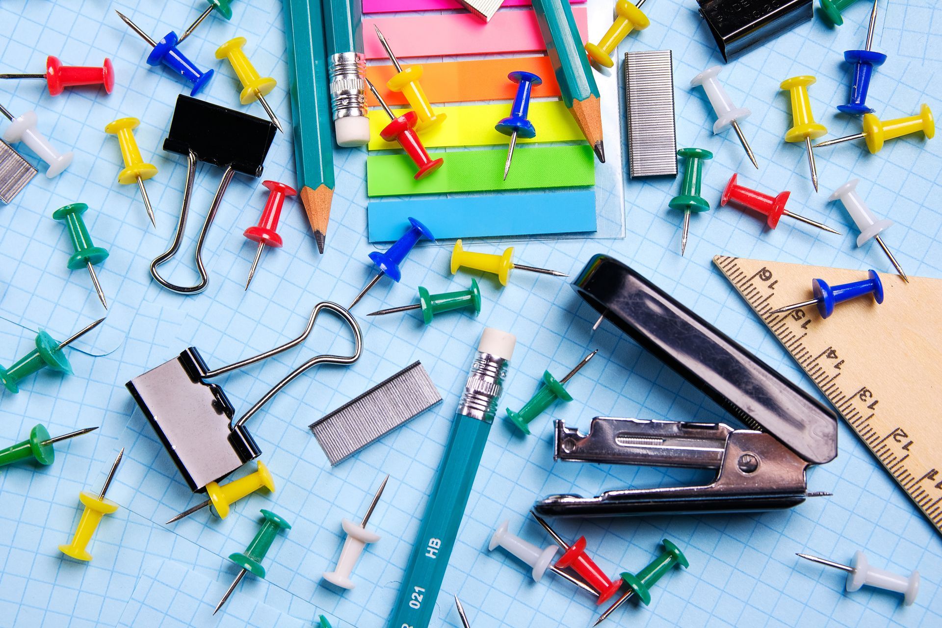 Office supplies on graph paper, including pins, pencils, clips, and stapler. Office supplies on graph paper, including pins, pencils, clips, and stapler.