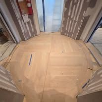 A circular, light-colored floor, partially covered with paper. Three door frames surround the floor.