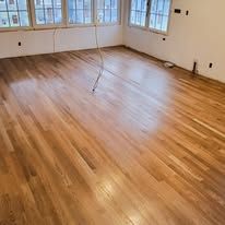 Hardwood floor in a room with light shining, and a wire attached to the floor.
