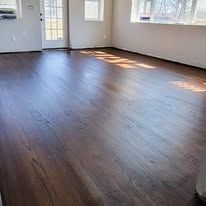 Dark wood-look flooring in a room with natural light from a window.