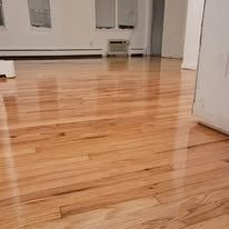 Shiny, light-colored hardwood floor in an empty room, reflecting light and the surroundings.