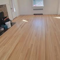 Light-colored hardwood floor in a room with a window, no furniture visible.