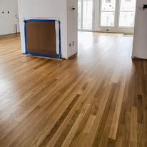 Newly installed hardwood floor in a room with a white wall and a covered opening.
