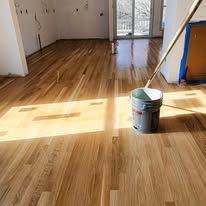 Wooden floor with sunlight, bucket, and mop in a room.