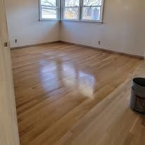 Hardwood floor in a room with windows reflecting light.
