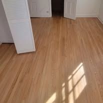 Hardwood floor in a room, with sunlight creating shadows.