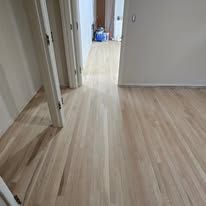 Wooden floor, two doorways, and a hallway. Light brown hardwood floor.