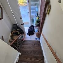 Wooden staircase, entryway with storage, and partial view of a door.