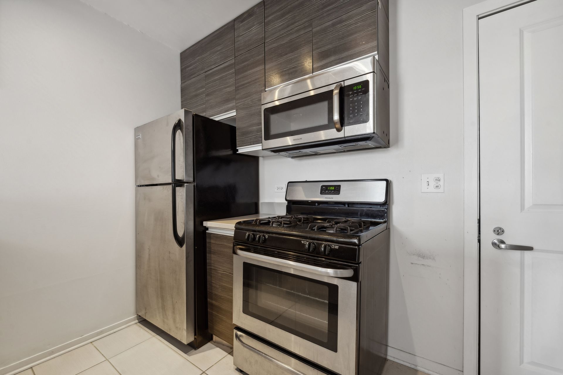 A kitchen with a stove , refrigerator , microwave and oven.