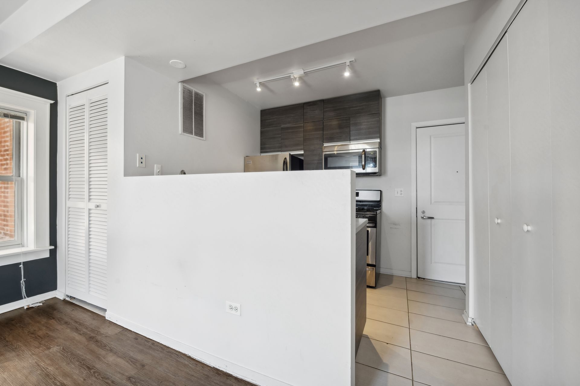 A kitchen with a stove , microwave , refrigerator and a counter.