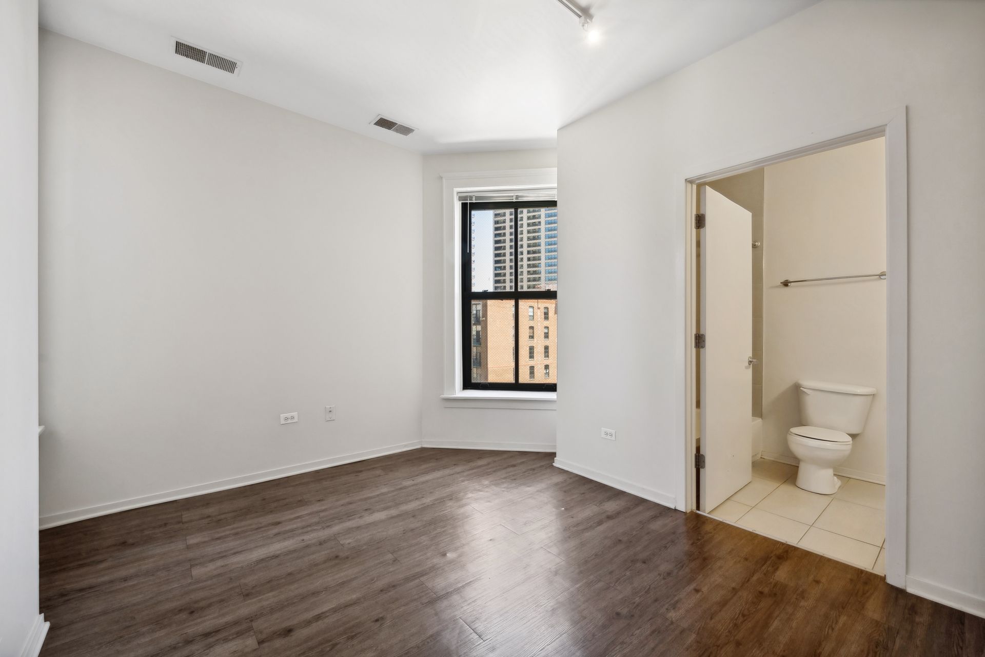 An empty room with a toilet and a window.