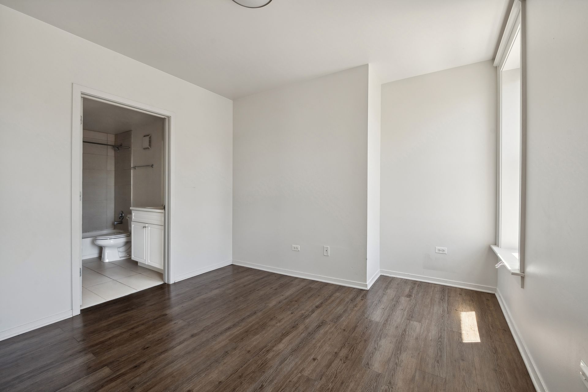 An empty room with hardwood floors and white walls