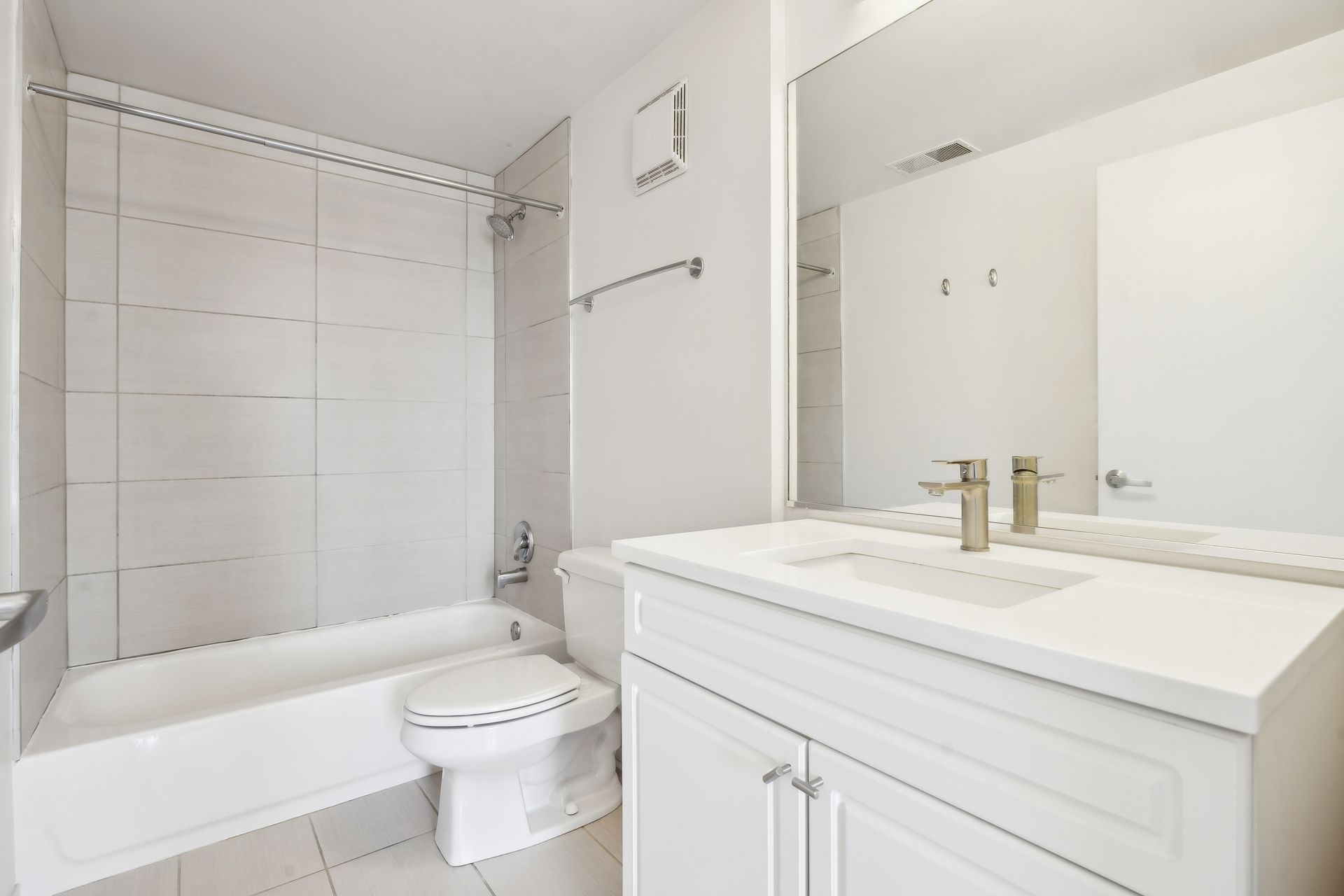 A bathroom with a toilet , sink , tub and mirror.