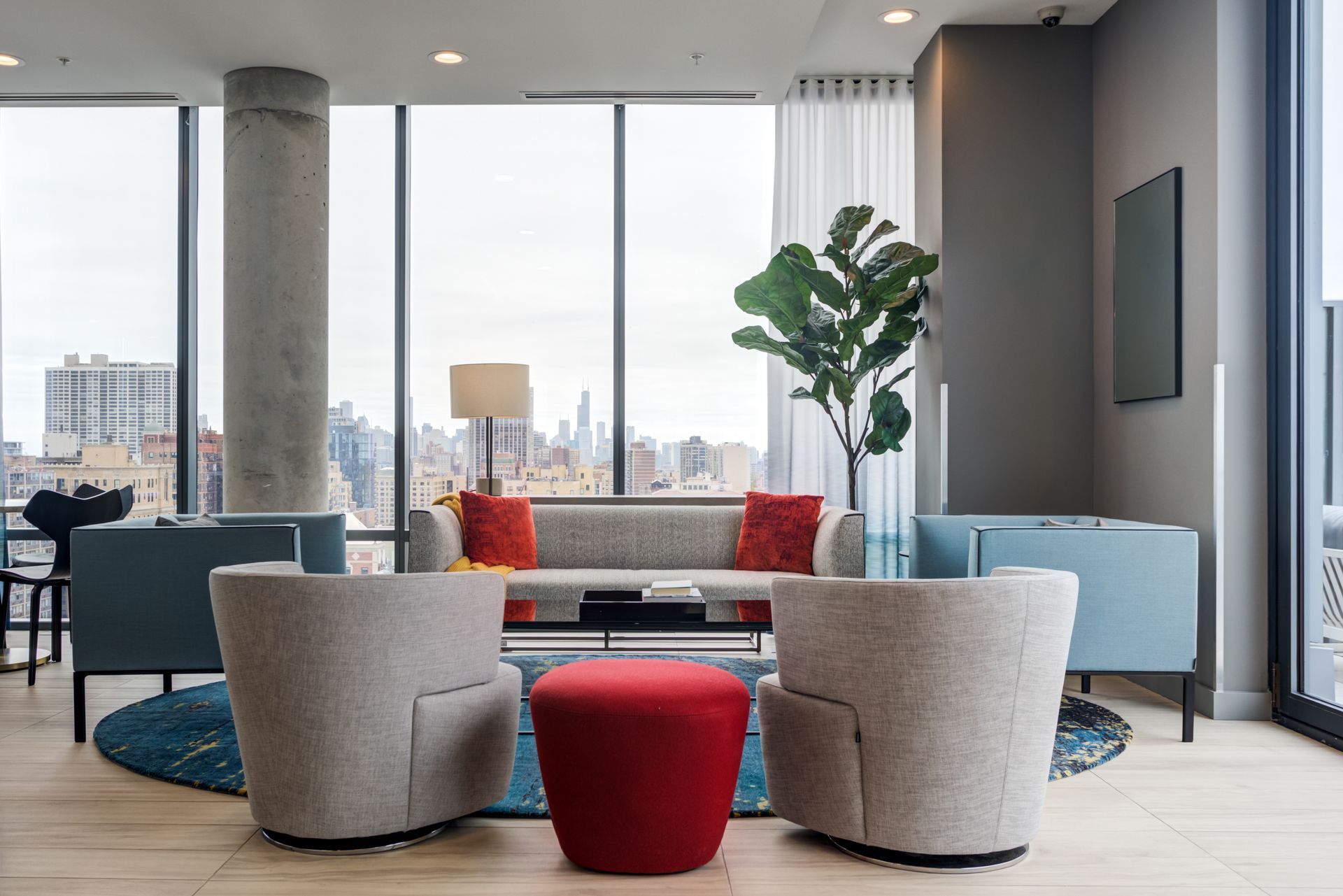 A living room with a couch , chairs , and a red ottoman.