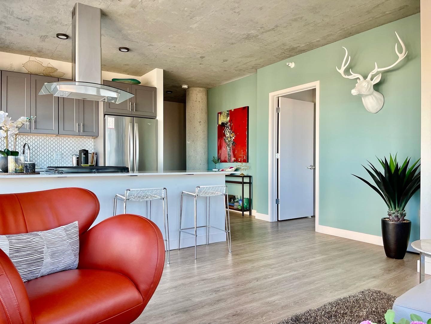 A living room with a red chair and a deer head on the wall