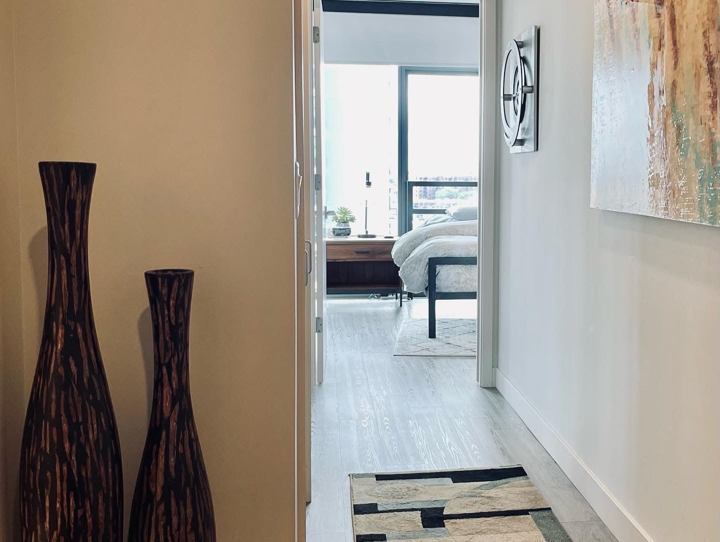 A hallway with two vases and a rug leading to a bedroom.
