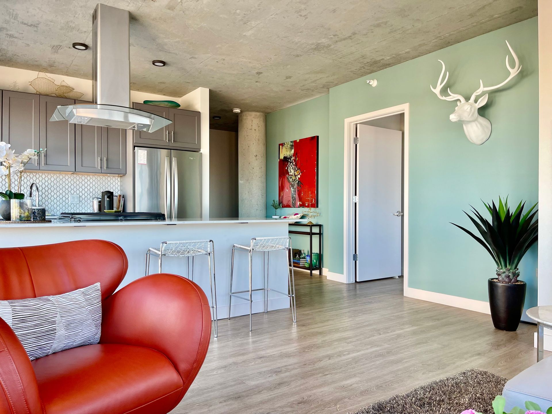 A living room with a red chair and a deer head on the wall