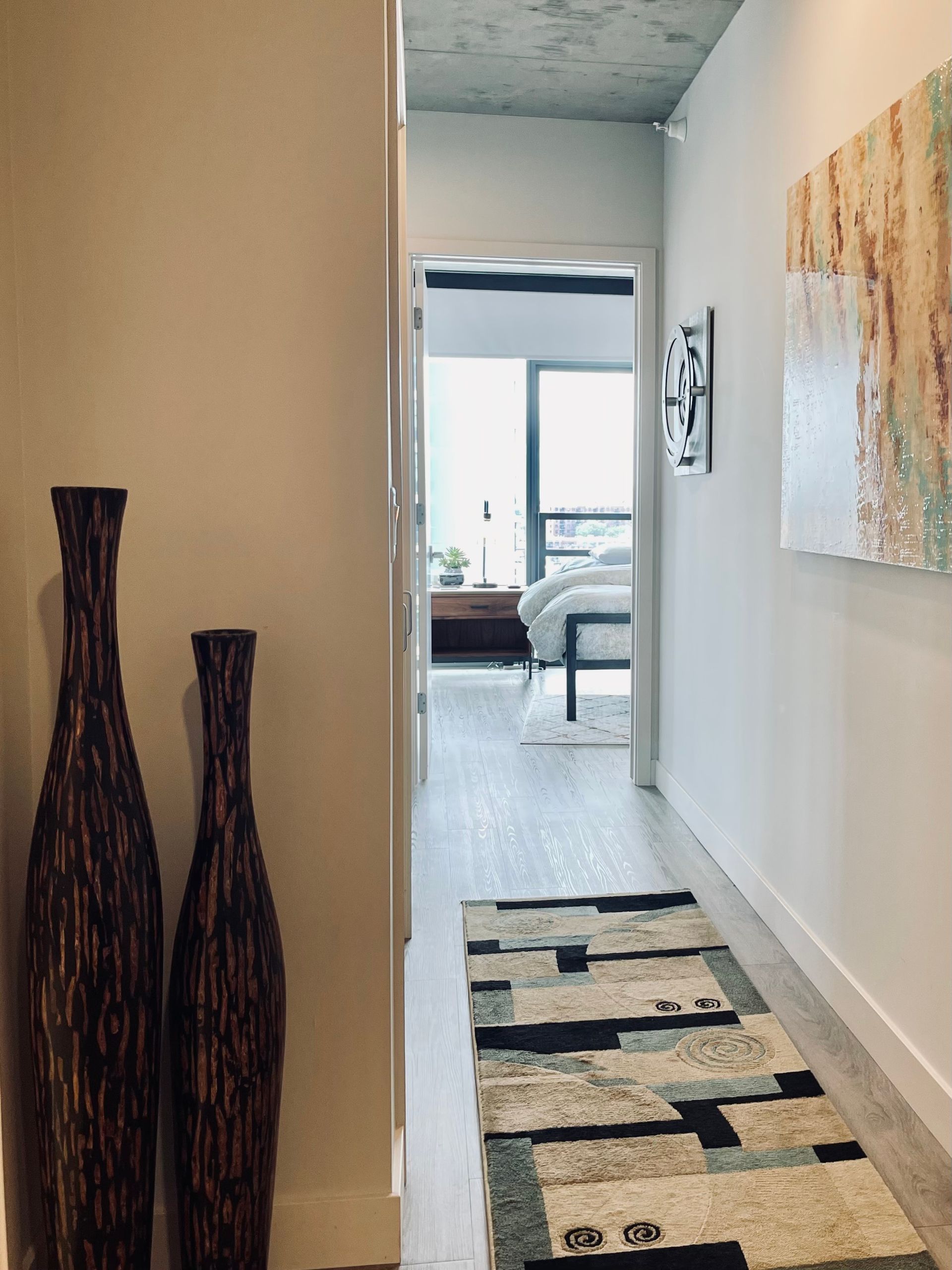 A hallway with two vases on the wall and a rug on the floor.