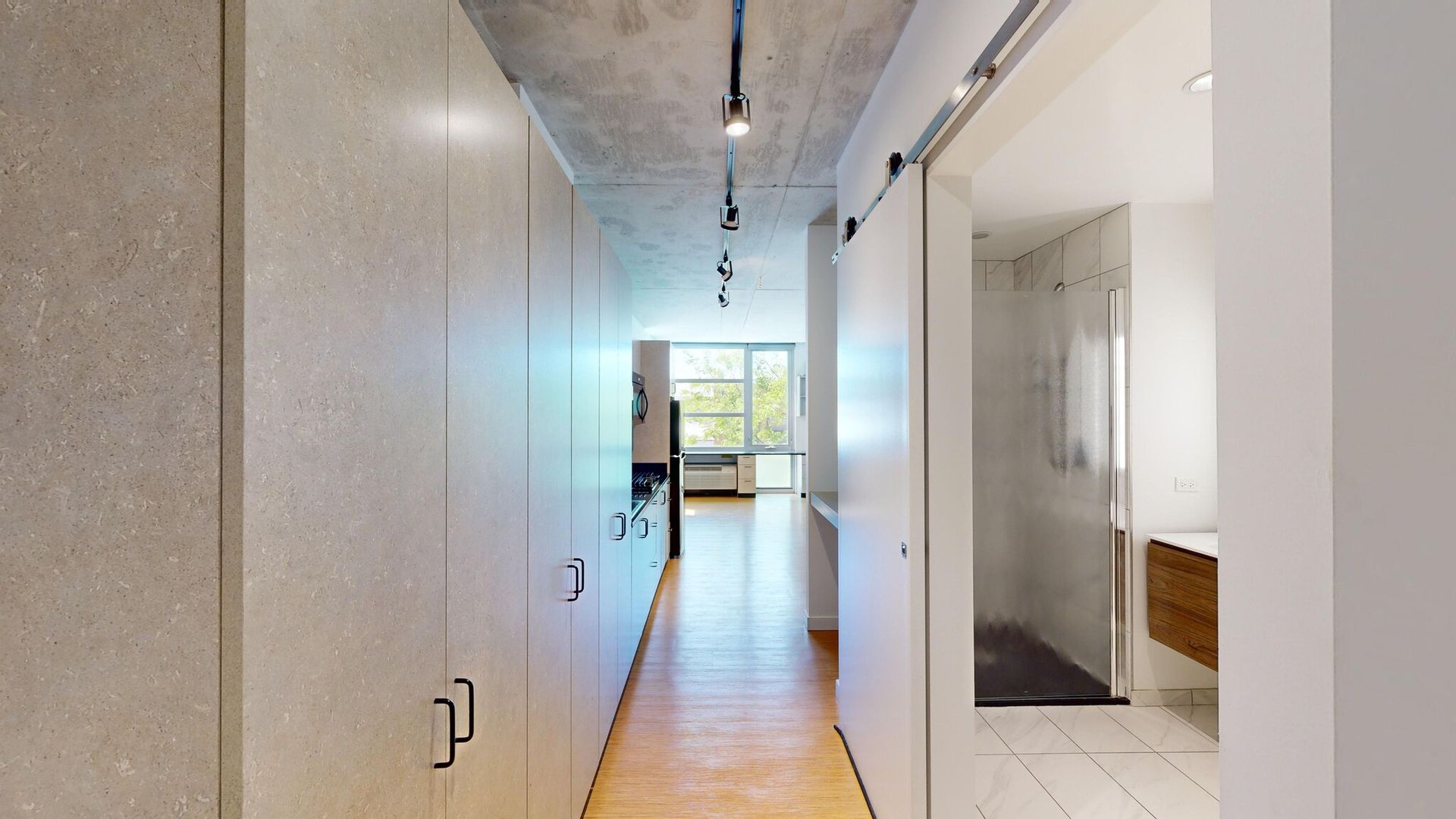 A long hallway with a sliding barn door leading to a bathroom.