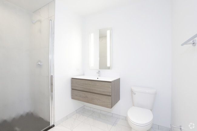 A bathroom with a toilet , sink , mirror and shower.