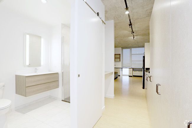 A hallway leading to a bathroom with a sink and mirror